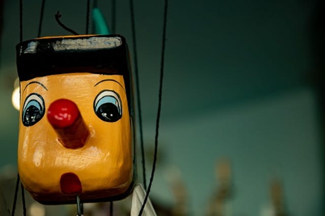 wooden Pinocchio on a puppet string, nose growing