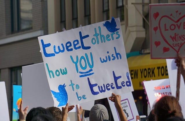 photo of people holding a sign that says tweet others how YOU wish to be tweeted