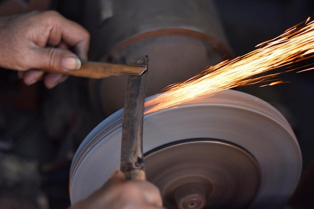 Person grinding on abrasive cutting and knife sharpening stones.