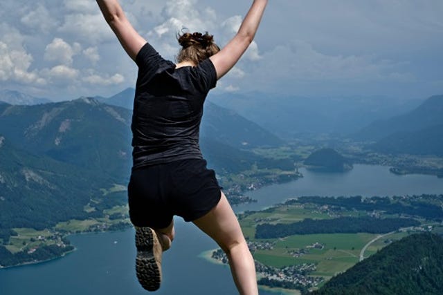 athletic woman leaping off a cliff toward water