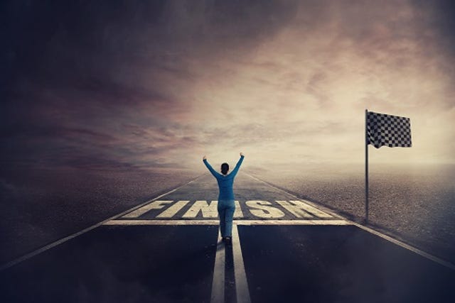 woman at a racing finish line hands up triumphantly