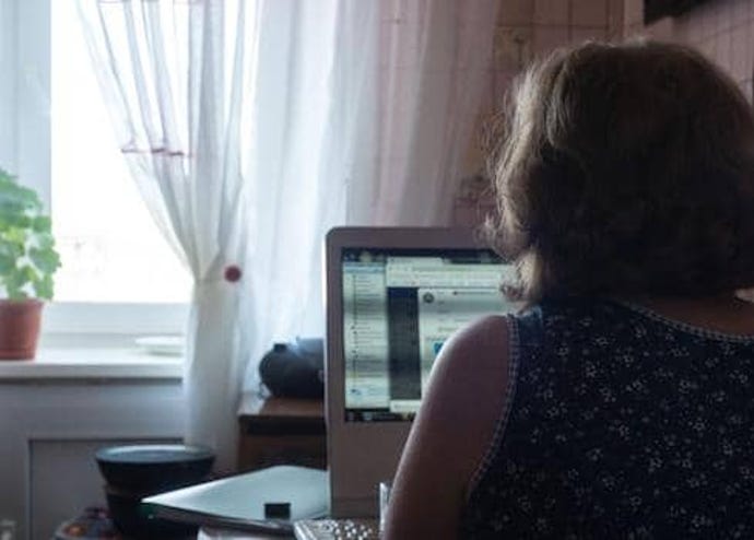 Successful businesswoman working at computer in her kitchen at home.