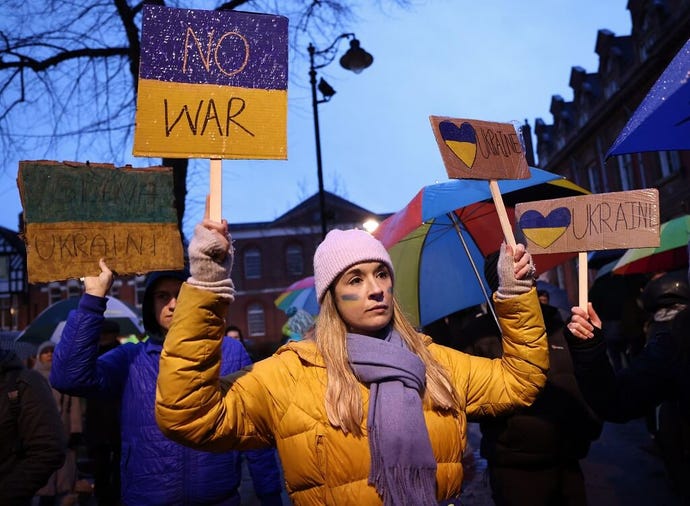 A demonstrator in a yellow jacket and blue scarf attends a vigil after Russian President Putin ordered invasion of Ukraine.