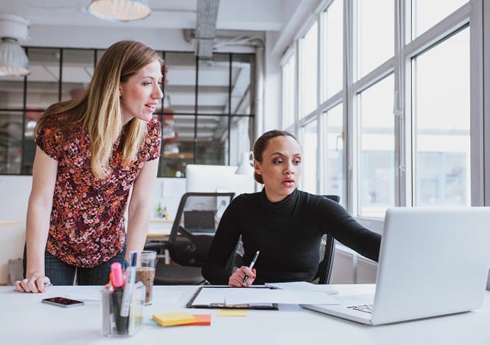 two female IT professionals consulting at a laptop